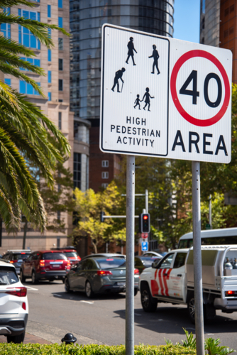 Speed limit and traffic caution sign with city and cars in background - Australian Stock Image