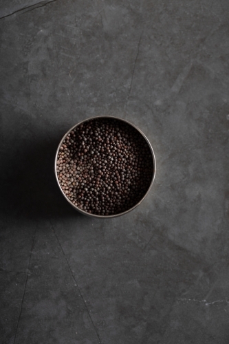 Spice tin of black mustard seeds on a dark marble background - Australian Stock Image