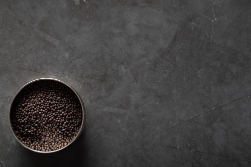 Spice tin of black mustard seeds on a dark marble background - Australian Stock Image
