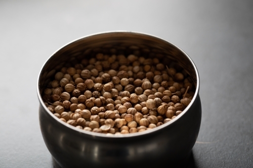 Spice tin of coriander seeds on dark marble background - Australian Stock Image