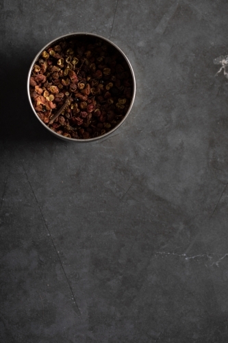 Spice tin of Sichuan pepper on dark marble background - Australian Stock Image
