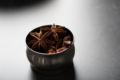 Spice tin of star anise on dark background