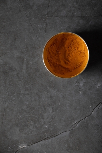 Spice tin of turmeric on dark marble table - Australian Stock Image