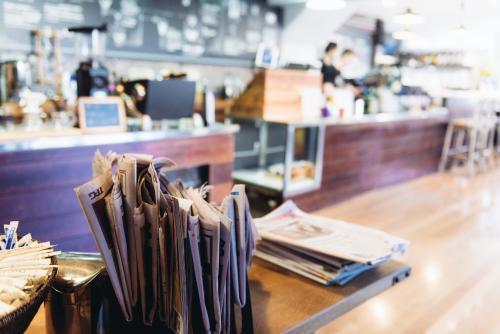 Stack of newspapers in cafe with service area in background - Australian Stock Image