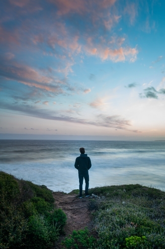 Man Standing on the Edge of a Great Ocean Road Cliff At Sunset - Australian Stock Image
