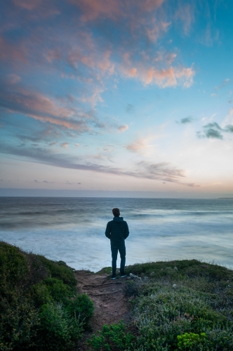 Man Standing on the Edge of a Great Ocean Road Cliff At Sunset