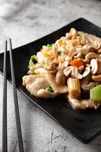 Steamed chicken stir fry on black plate - Australian Stock Image