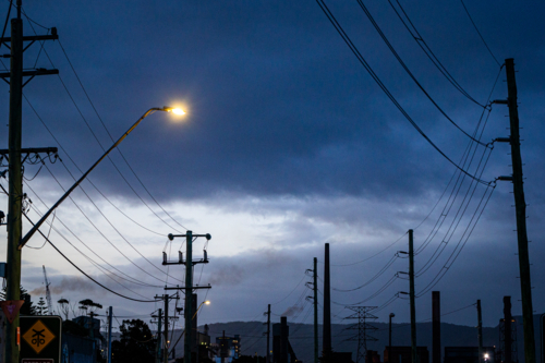 Steel smelter stacks behind silhouetted power lines - Australian Stock Image