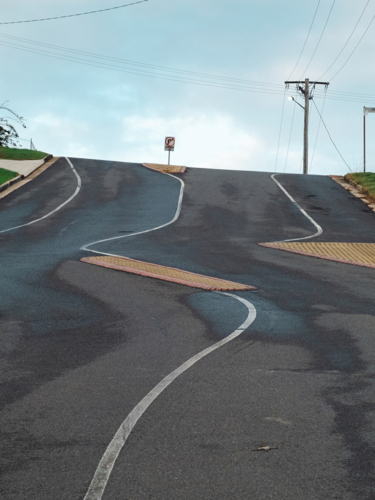 Steep, sealed road leading uphill toward the horizon - Australian Stock Image