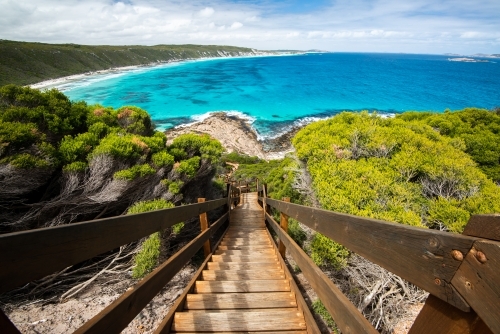 Steps leading down to rocks and colourful ocean  with sweeping views of coastline - Australian Stock Image
