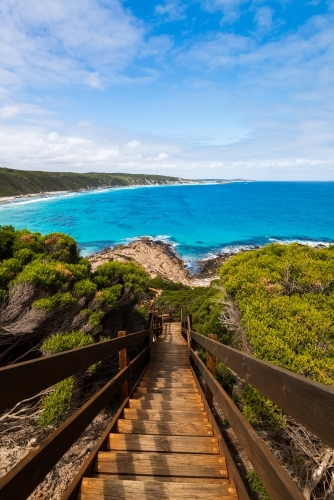 Steps leading down to rocks and colourful ocean  with sweeping views of coastline in portrait - Australian Stock Image