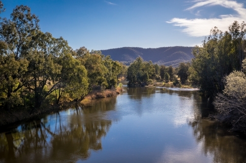 Still lake surrounded by mountains and trees - Australian Stock Image
