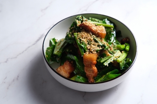 Stir-fried green leafy vegetable with pork belly slices garnished with crushed peanuts. - Australian Stock Image