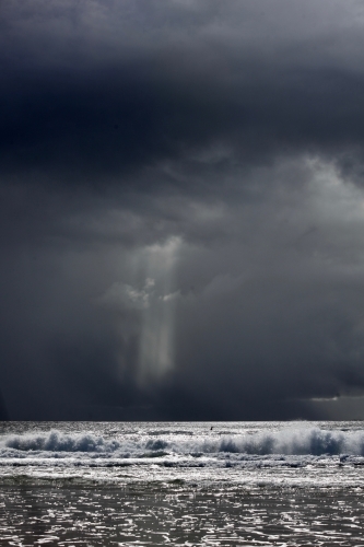 Storm behind ocean, surfer in distance, space above