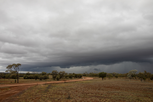 Storm front rolling past over a gravel road - Australian Stock Image