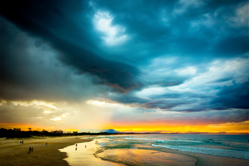 Storm-lit sunset over a quiet coastal beach. - Australian Stock Image