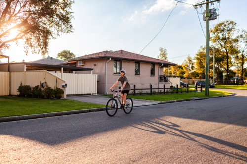 Street in country town with boy riding past on bike - Australian Stock Image