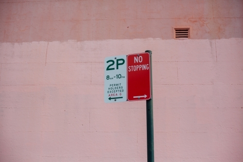 Street parking signs against pink wall