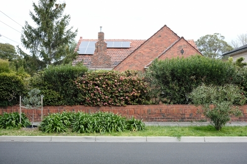 Street view of an old brick house surrounded by garden