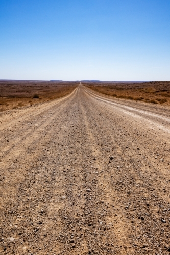stretch of dirt road in desert landscape, vertical - Australian Stock Image