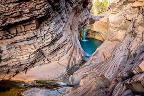 Striking rock layers lead into a turquoise pool beneath soft morning light. - Australian Stock Image