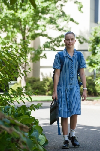 Student walking through school grounds with laptop - Australian Stock Image