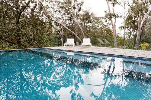 Stunning blue tiled infinity swimming pool in Australian home with bush garden setting - Australian Stock Image