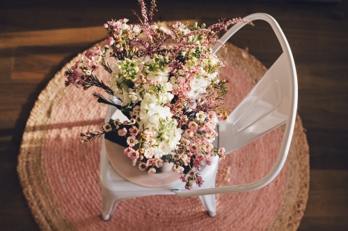 Stunning fresh flowers on a chair and pink rug from overhead - Australian Stock Image