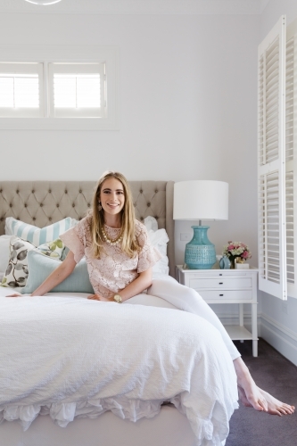 Stylish young woman in a hamptons styled bedroom - Australian Stock Image