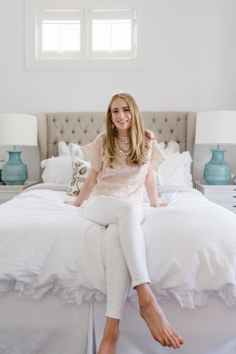 Successful young blonde woman in her bedroom smiling - Australian Stock Image