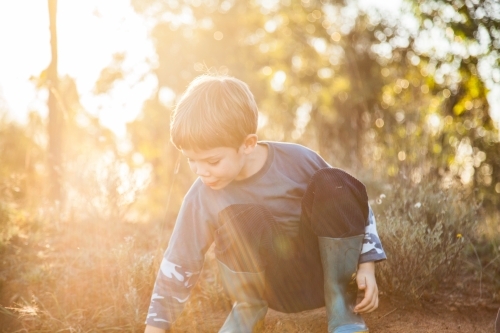 Sun flare over child playing in the dirt - Australian Stock Image