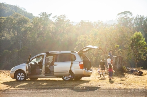 Sun flare over family car stopped beside rural road dad and children beside vehicle - Australian Stock Image
