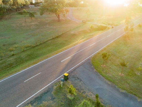 Sun flare over rural road and recycling bins - Australian Stock Image