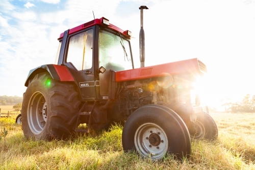 Sun flare through tractor in paddock on farm - Australian Stock Image