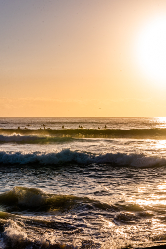 Sun Glare Over Breaking Waves and surfers - Australian Stock Image