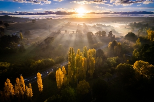 Sun ray beams covering the countryside as the fog covers the land - Australian Stock Image