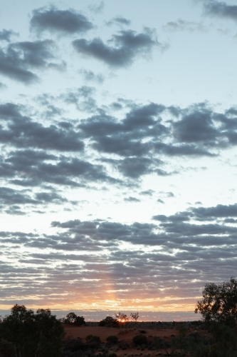 Sun rays breaking through the clouds with a sunset sky of blue, orange, and yellow - Australian Stock Image