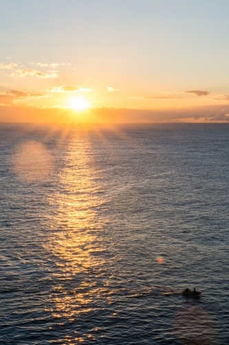 Sun reflecting on water with boat in foreground during sunrise - Australian Stock Image