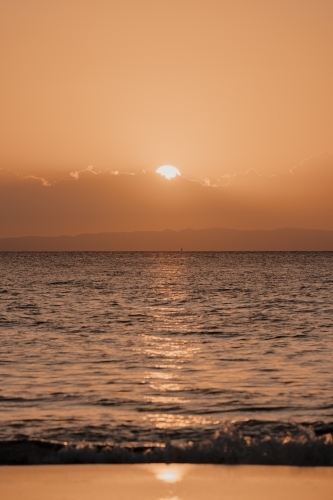 Sun setting behind the clouds over Moreton Bay - Australian Stock Image