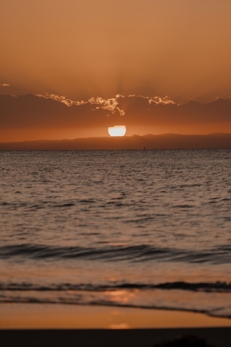 Sun setting behind the clouds over Moreton Bay - Australian Stock Image