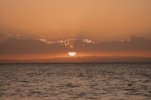 Sun setting behind the clouds over Moreton Bay - Australian Stock Image
