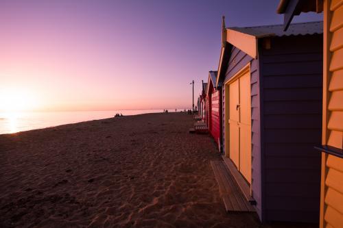 Sun setting on Brighton Bathing Boxes at Dendy Beach - Australian Stock Image
