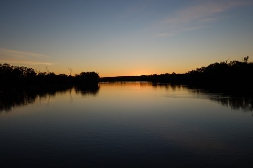 Sun setting over the River Murray in Victoria with calm reflections - Australian Stock Image