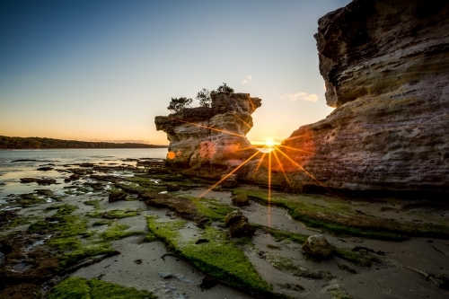 Sun setting through The Hole in the Wall at Jervis Bay - Australian Stock Image