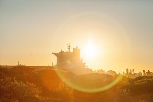 Sunlight on plant covered sand dunes and a boat