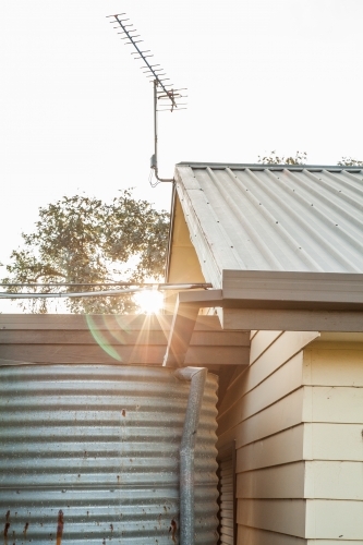 Sunlight shining past shed and rainwater tank