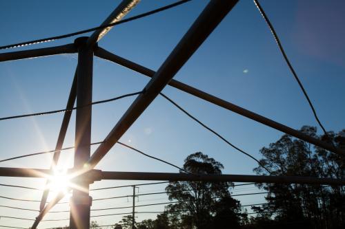 Sunlight shining through a hills hoist washing line silhouetted against sky - Australian Stock Image