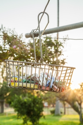 Sunlight shining through peg basket on washing line in backyard of country homestead - Australian Stock Image