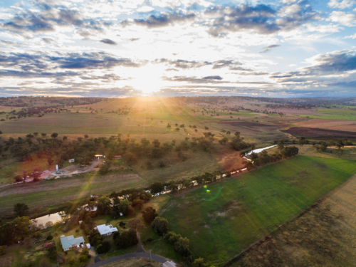 Sunlight streaming over river running through farmland in the Hunter region of New South Wales - Australian Stock Image