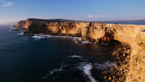 Sunlit cliffs surrounded by ocean - Australian Stock Image